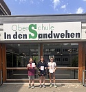 Die drei Gewinner stehen vor dem Eingang der Oberschule in den Sandwehen.
